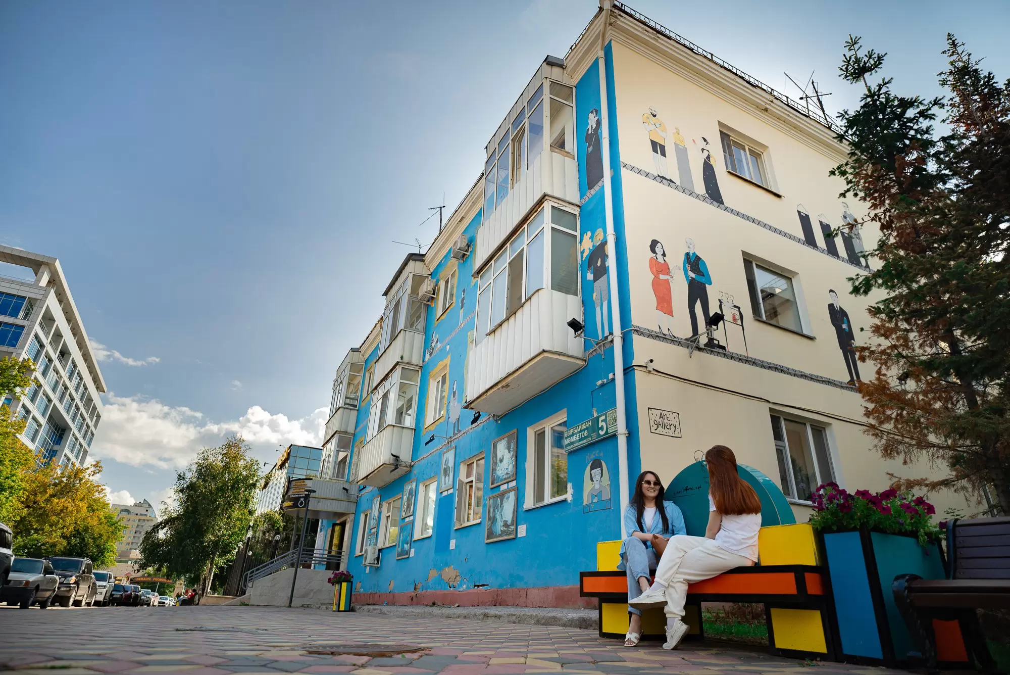 Women chat in front of a colorful apartment building in Astana, Kazakhstan.