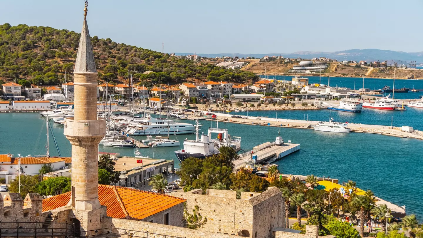 A view of a marina with various boats and a tall stone tower in the foreground.