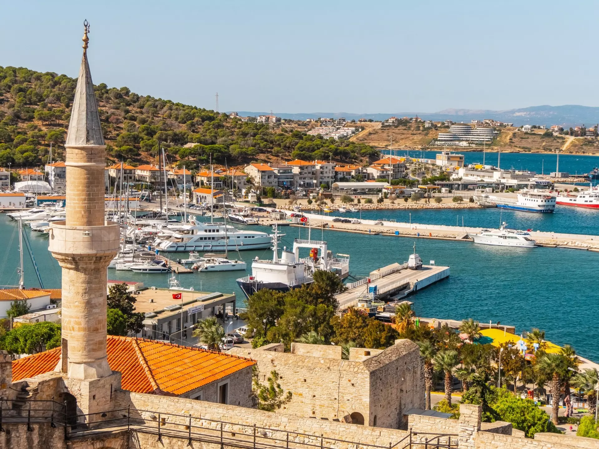 A view of a marina with various boats and a tall stone tower in the foreground.