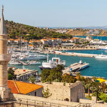 A view of a marina with various boats and a tall stone tower in the foreground.