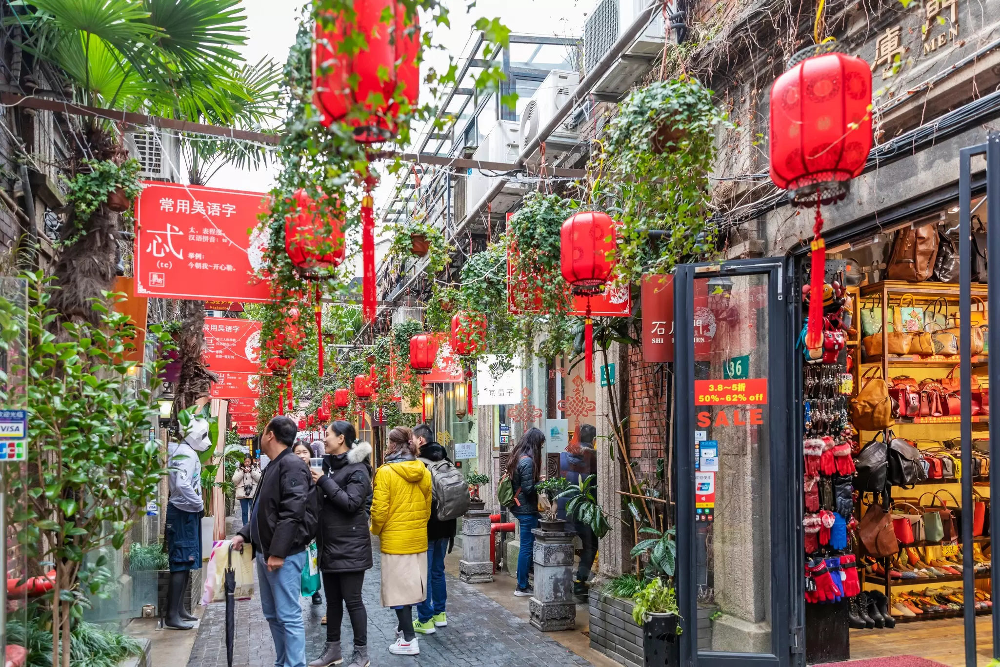 People walking under red lanterns in Tianzifang, a neighborhood of Shanghai, China.
