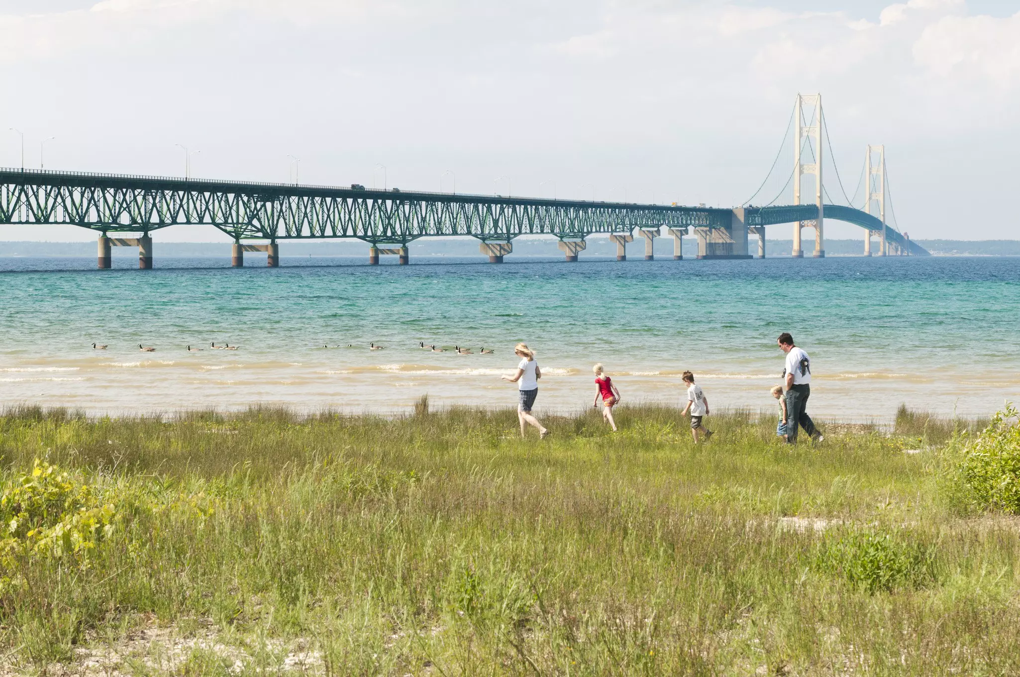 A family walks on the shore near Mackinac Bridge