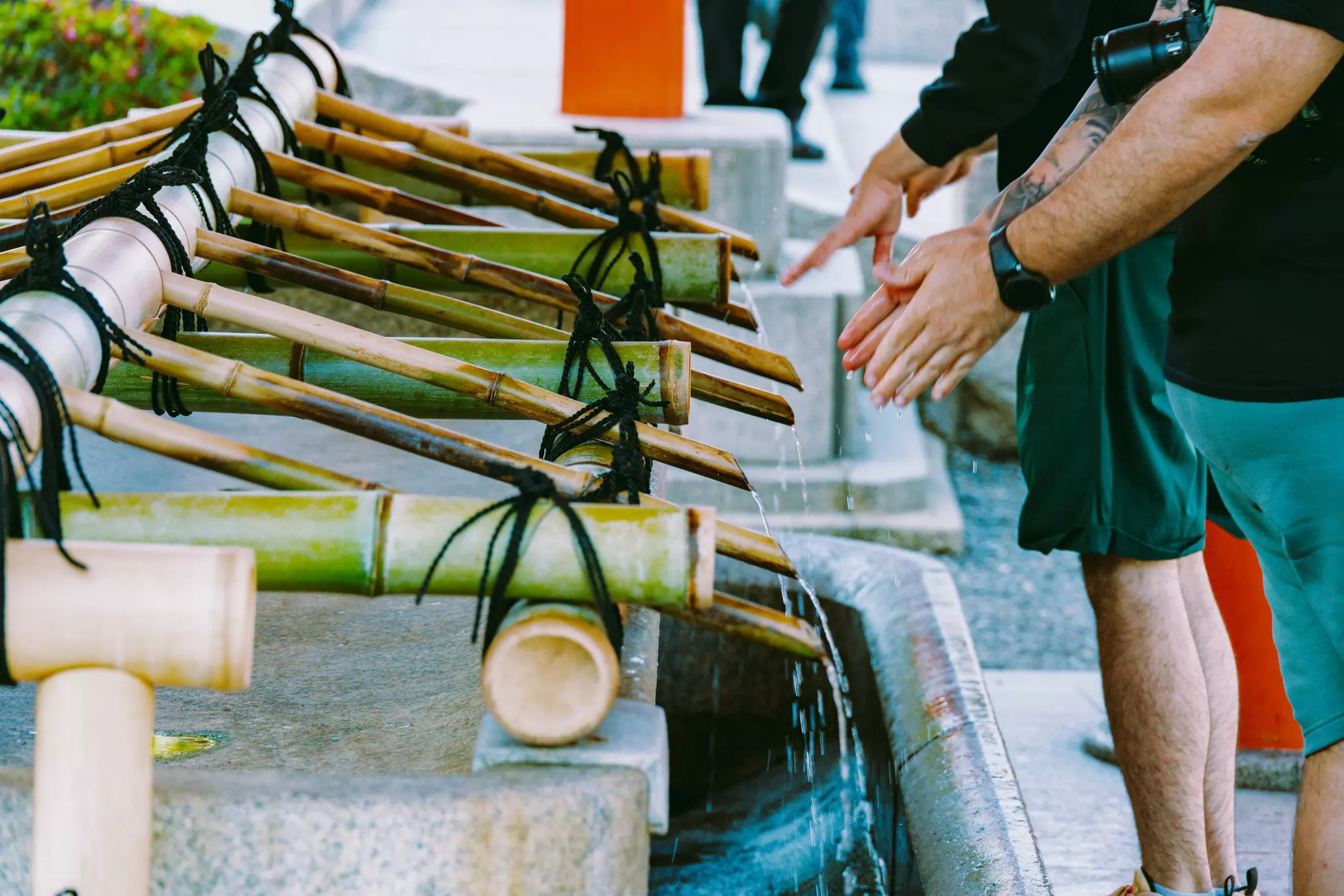 People wash their hands in a stone sink with bamboo spigots.
