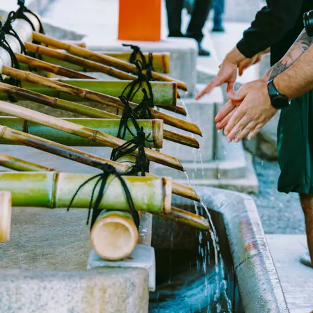 People wash their hands in a stone sink with bamboo spigots.