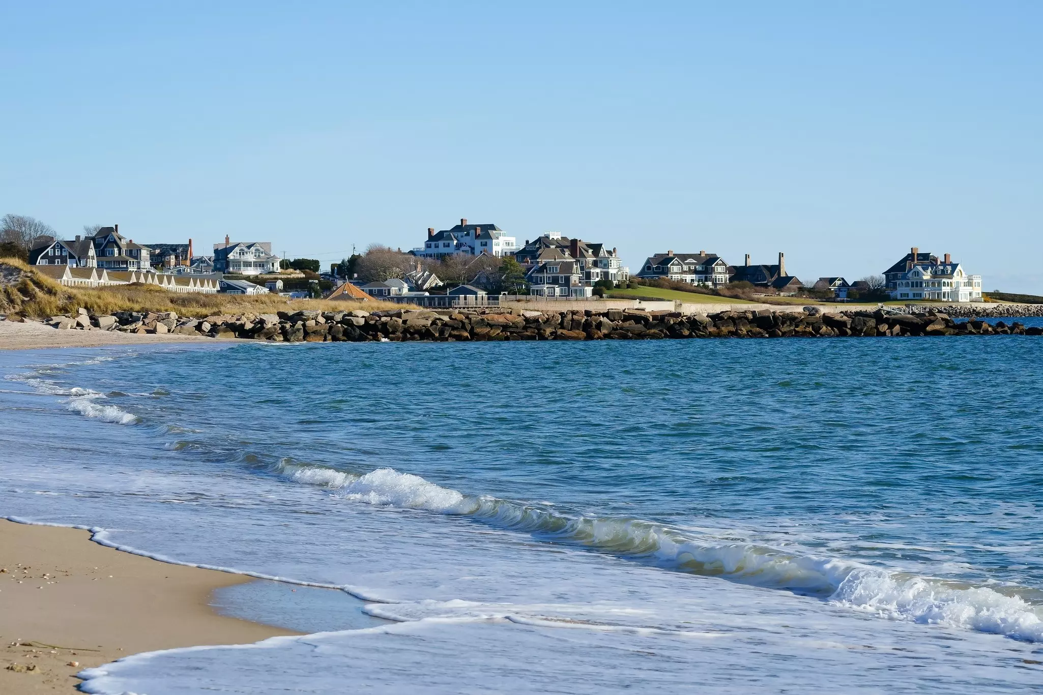 Large homes at the end of a sandy beach.
