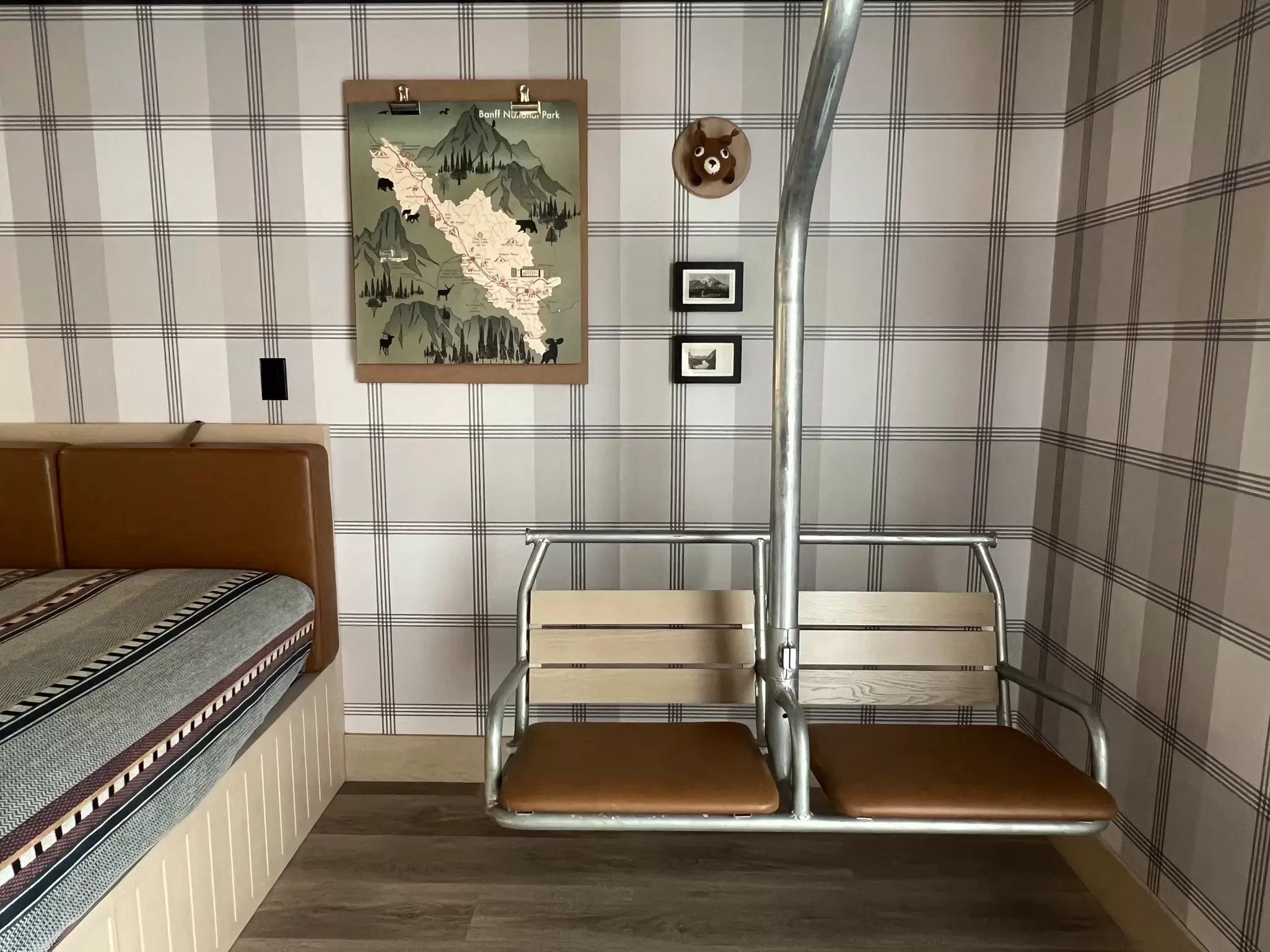 Chairs from a ski lift installed in a hotel room with gray plaid wallpaper.