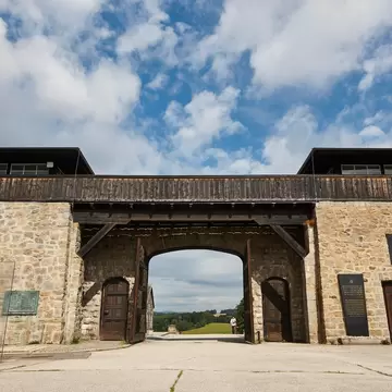 Granite gateway of the former Mauthausen camp, Austria, with timber guard towers, open doors and memorial plaques