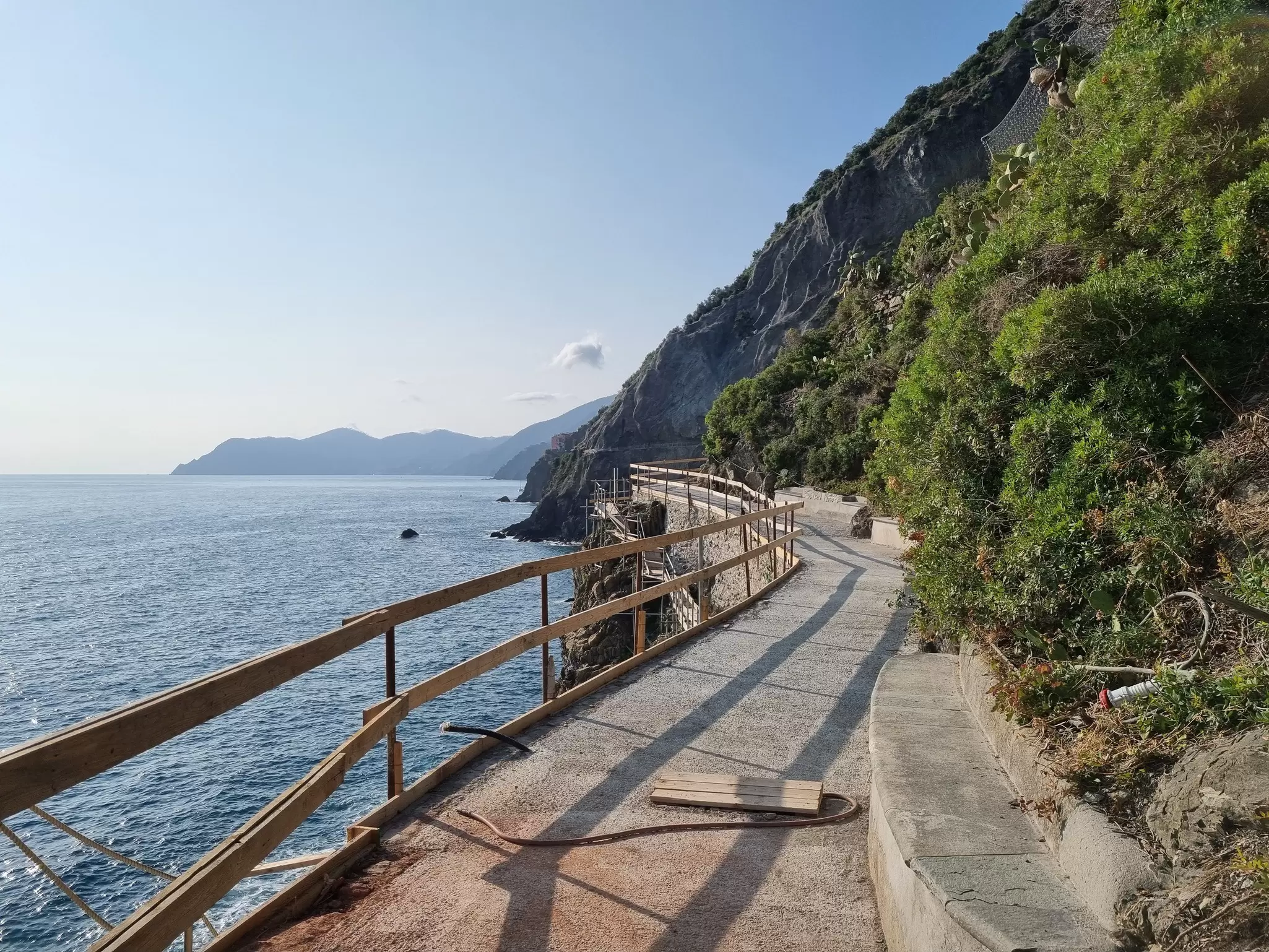 A cliffside path with a wooden safety fence on the sea side