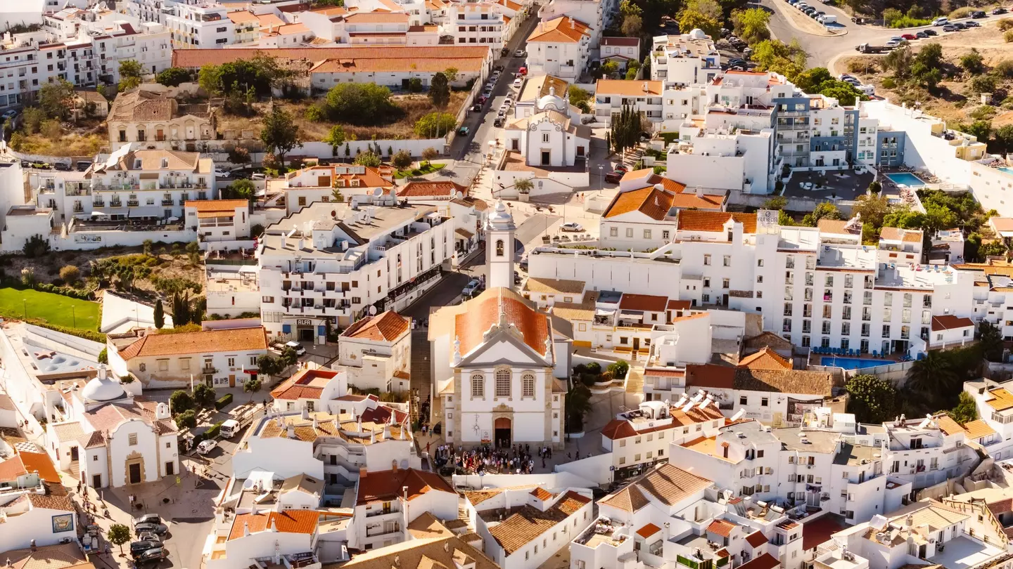 Aerial view of whitewashed buildings and churches on a sunny day in Albufeira, Portugal.