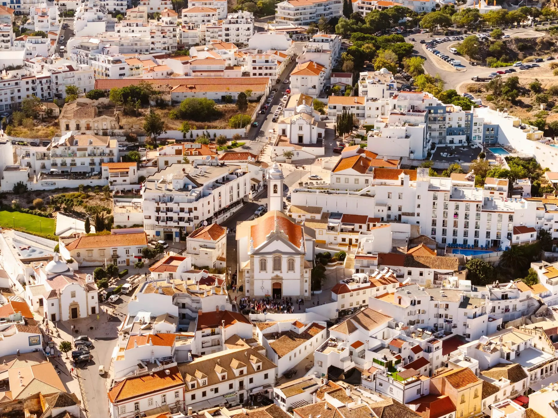 Aerial view of whitewashed buildings and churches on a sunny day in Albufeira, Portugal.