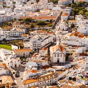 Aerial view of whitewashed buildings and churches on a sunny day in Albufeira, Portugal.
