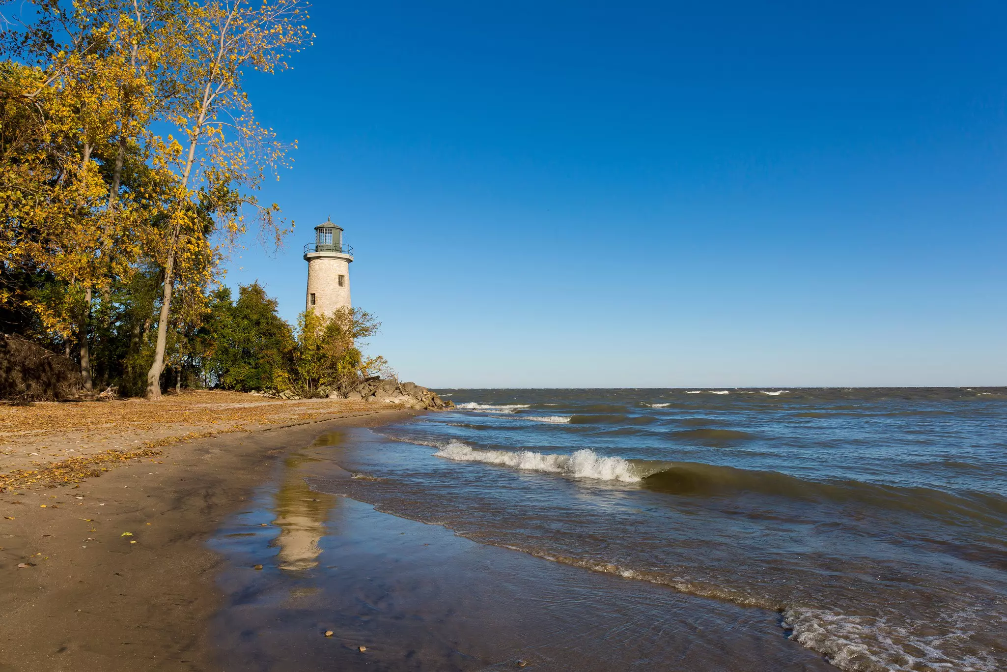 A lighthouse rises by a beach gently lapped by waves, Pelee Island, Ontario