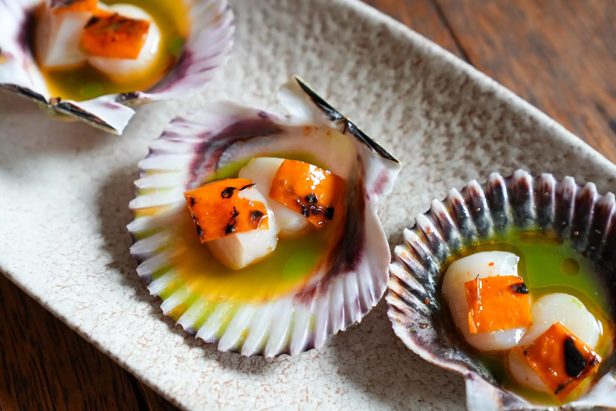 Raw fish presented within shells on a plate in a restaurant.