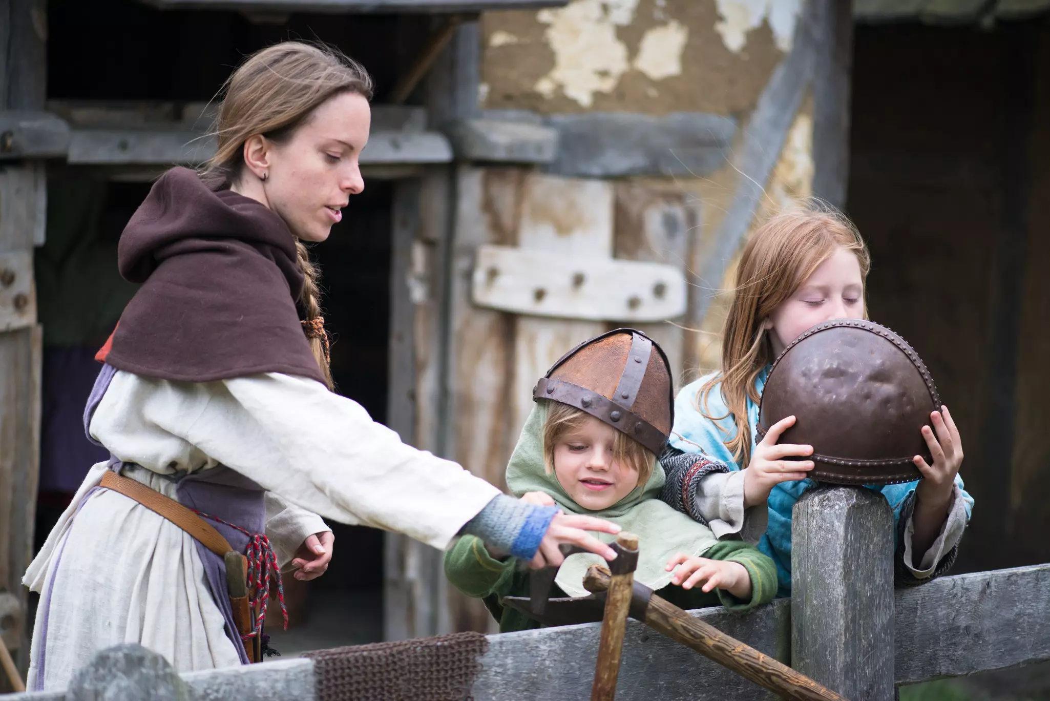 A woman and two children wear Viking costumes at a historical-reenactment museum.