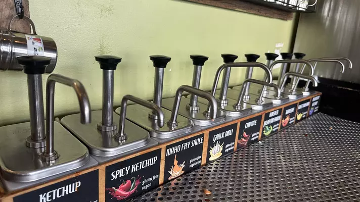 Self-serve cans of different flavors of fry sauces all in a row