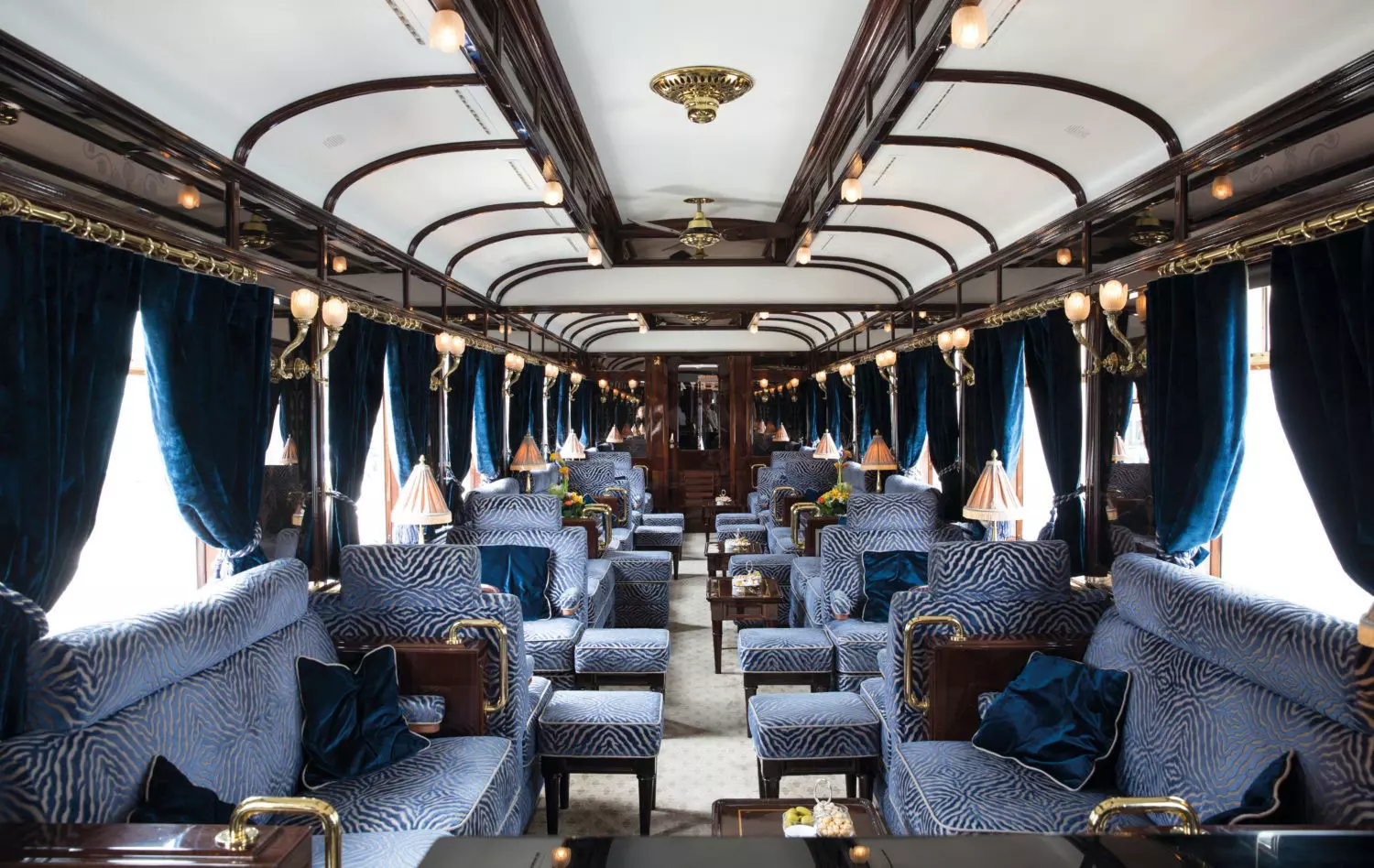 A well-appointed train car with upholstered seating and dark wood accents.