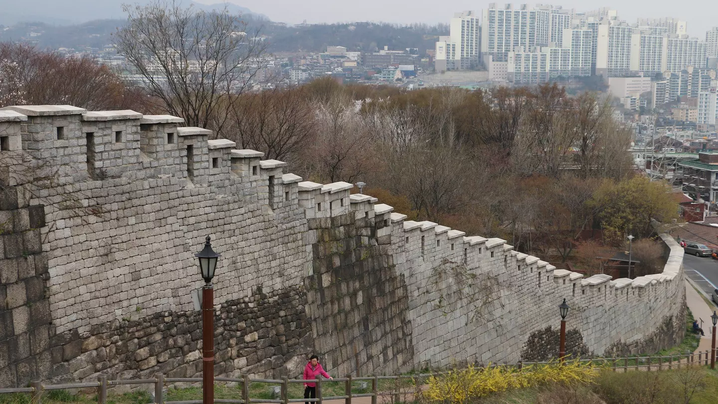 The old Seoul city walls with the skyline of Seoul in the distance, along a path in Naksan Park