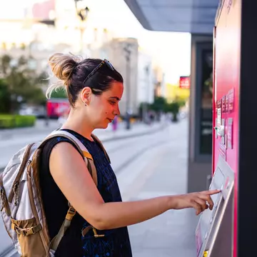 Young woman buying ticket for transportation