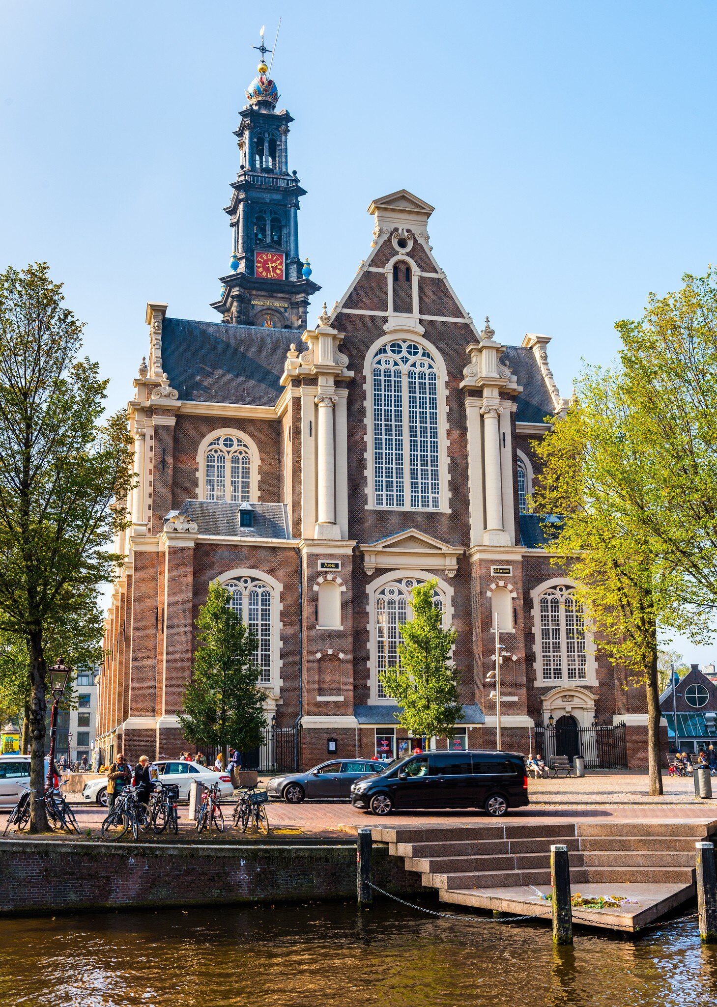 Exterior view of Westerkerk from across the canal on a sunny day in Amsterdam.