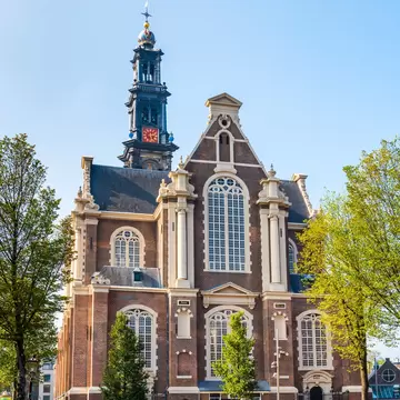 Exterior view of Westerkerk from across the canal on a sunny day in Amsterdam.