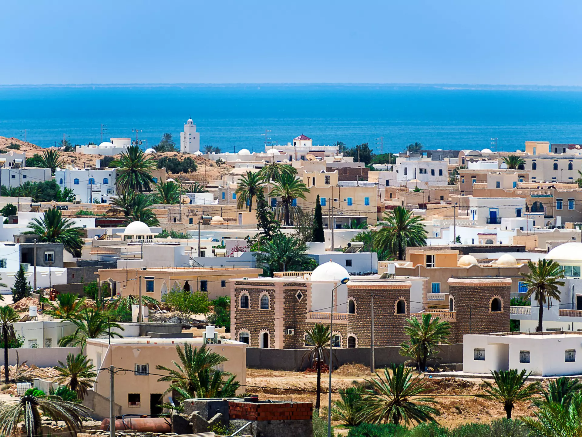 A view of a town with white and beige buildings by the ocean