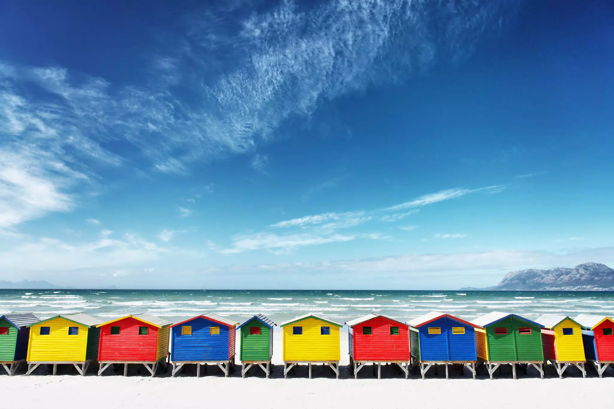 A row of wooden beach huts painted in bright colors.