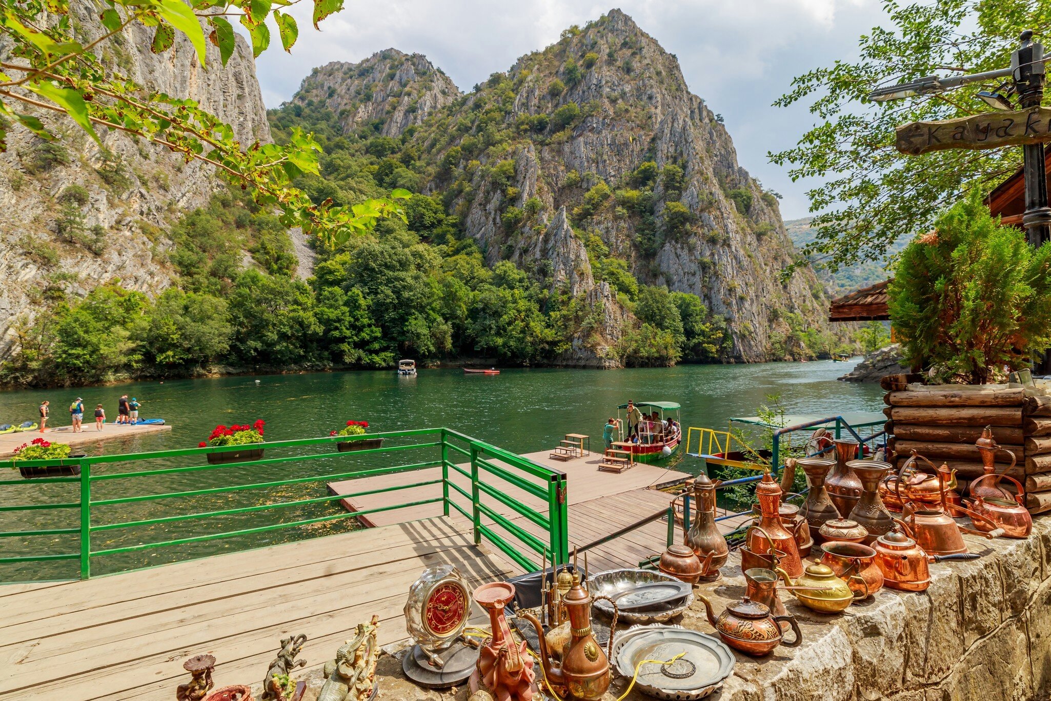 Copper teapots on a ledge above a boat jetty on the green lake of Matka Canyon near Skopje, North Macedonia