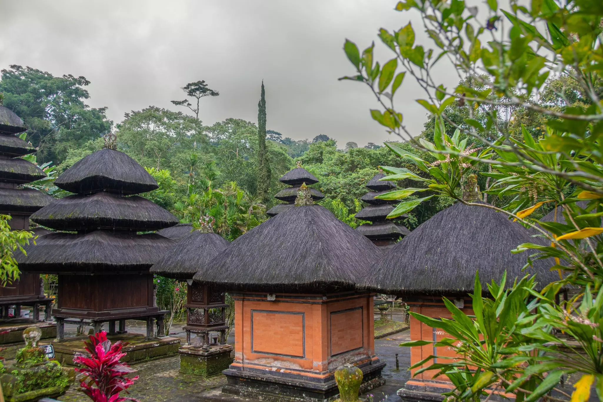 The grounds of the Pura Luhur Batukaru temple in Bali with green, yellow and fuchsia plants on an overcast day