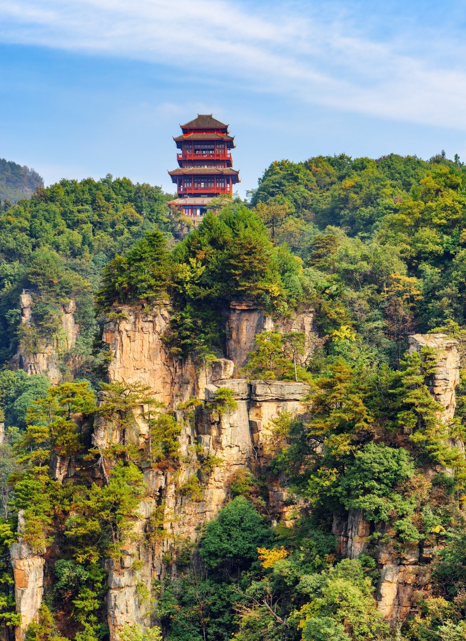 Red temple atop of mountain covered in trees