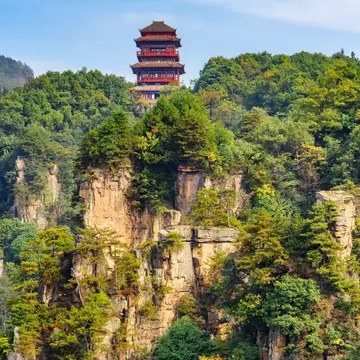 Red temple atop of mountain covered in trees