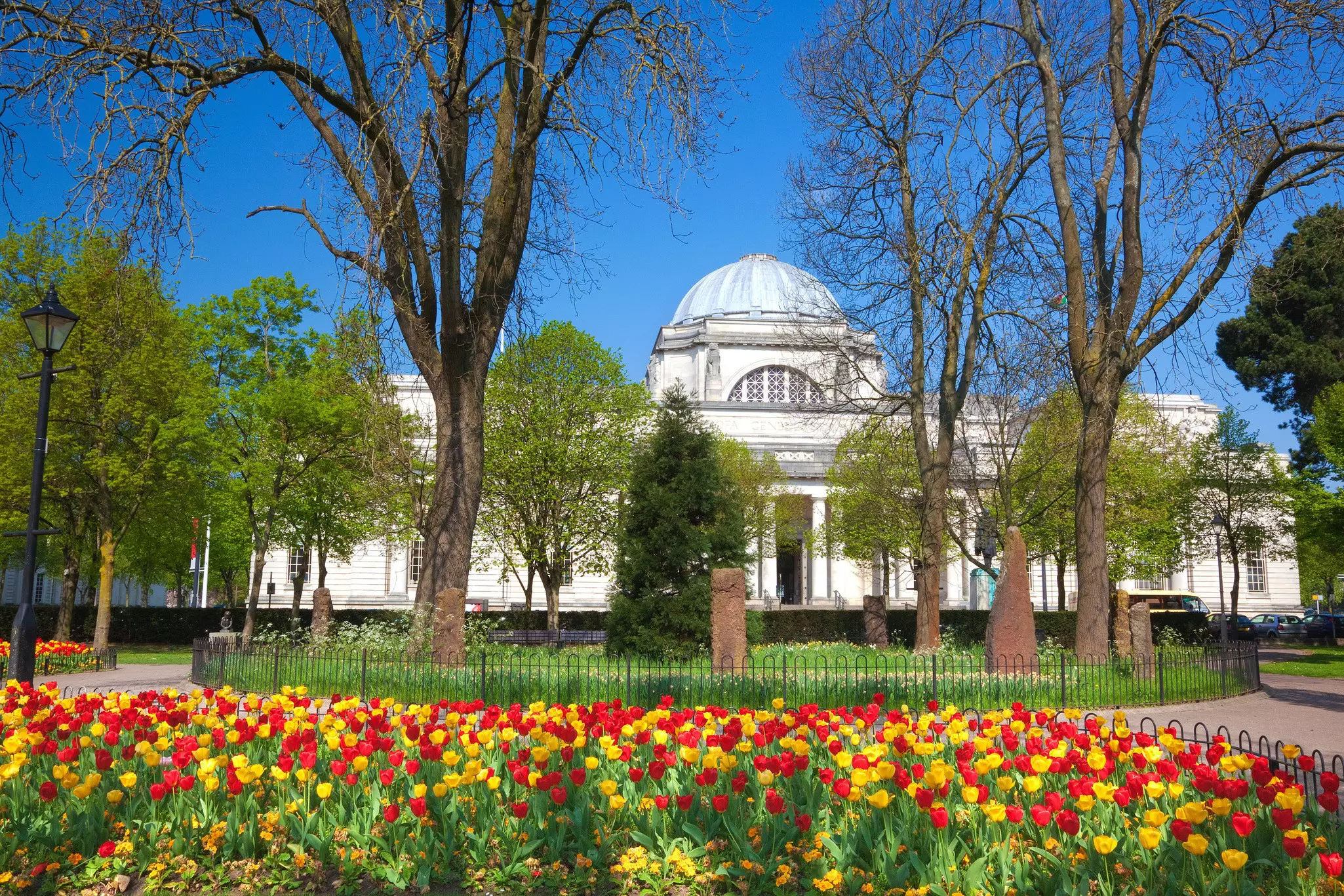 A grand museum building set in parkland with tulips in bloom