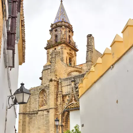 A Spanish side street with gas lanterns, whitewashed buildings and views of a medieval church