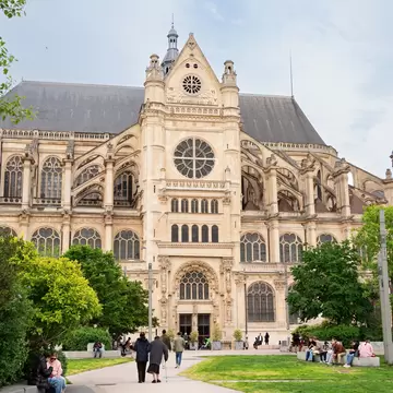 Front of Church of Saint-Eustache from the public square with people relaxing on a sunny spring day.
