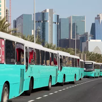 A line of turquoise buses line up along the Corniche of Doha at the Qatar National Day
