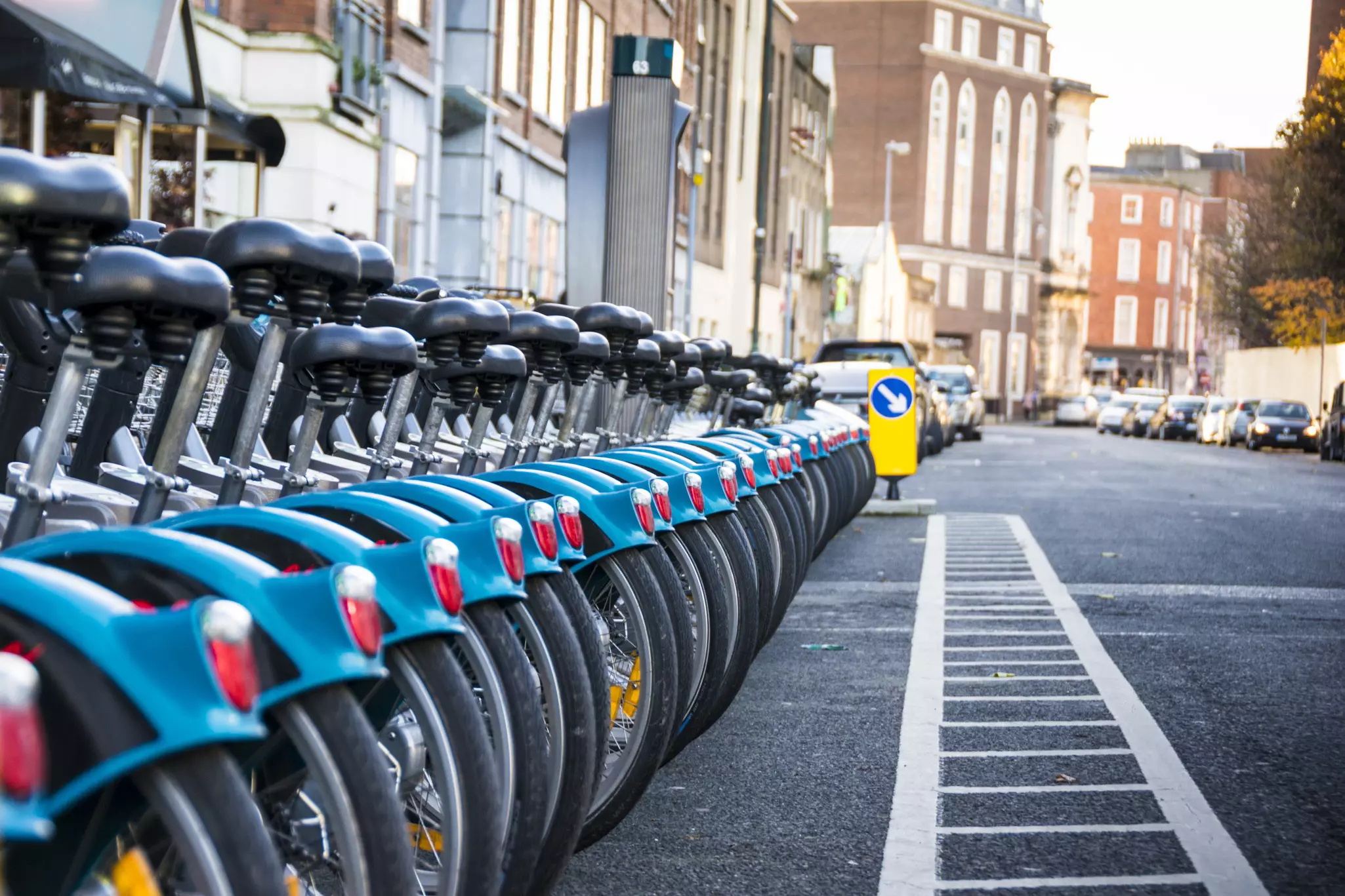 The back tires of a public bikes lined up at a stand on a street