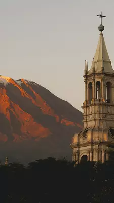 A church tower with a red mountain in the background.