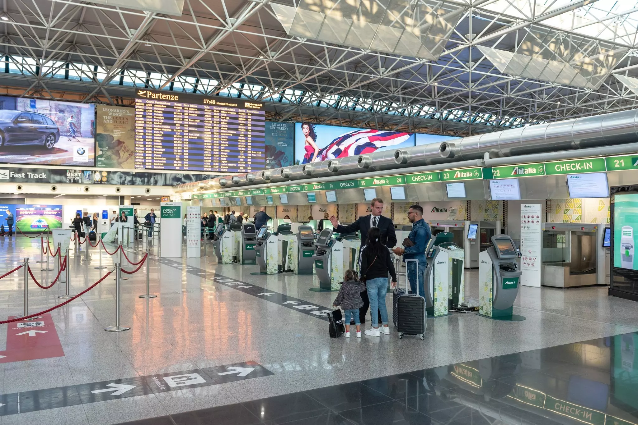 Passengers speak with an airline agent by the Alitalia check-in desks at Rome's main airport.