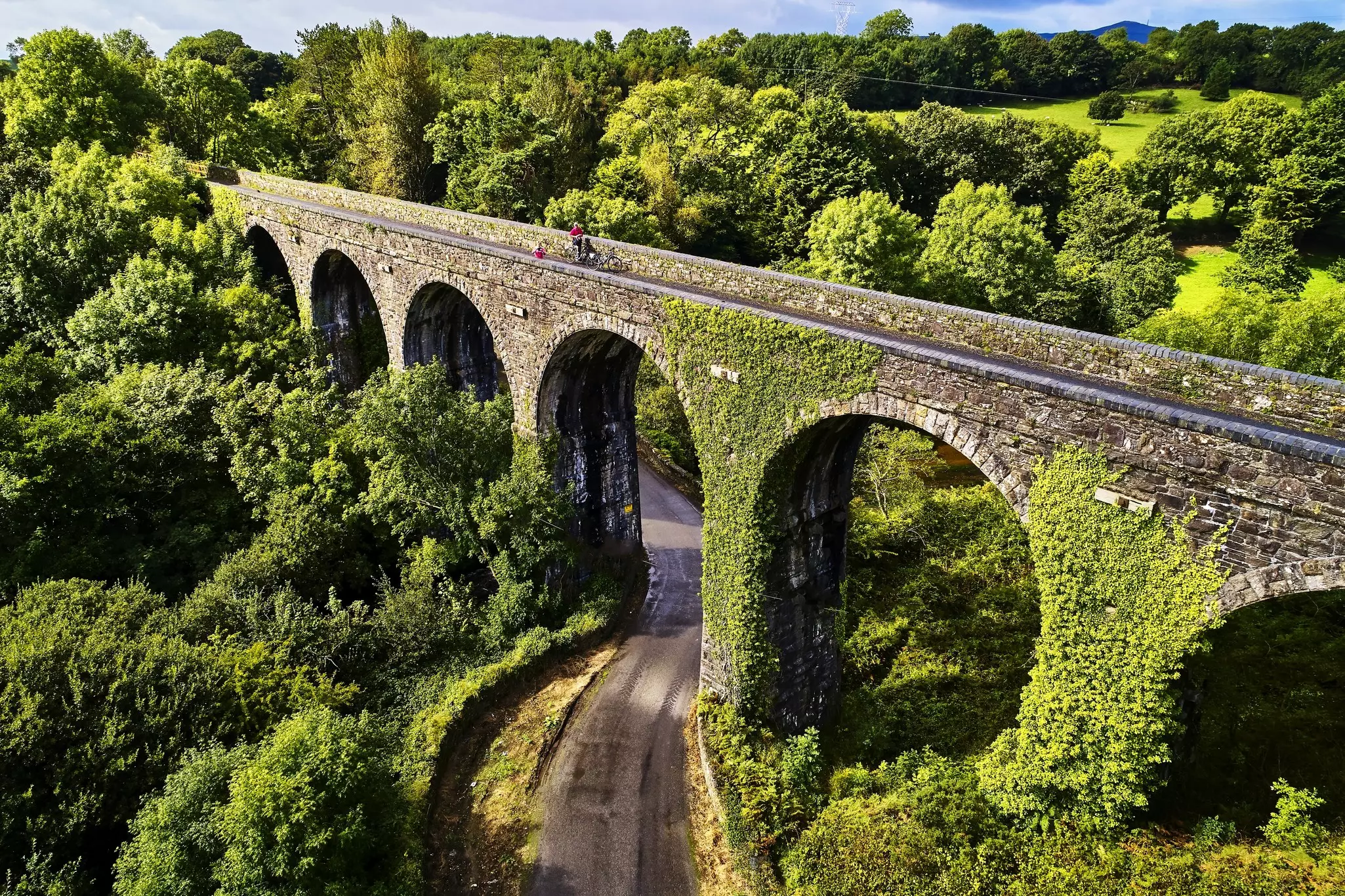 Cyclists stop on an aqueduct along Ireland's Greenway route. 