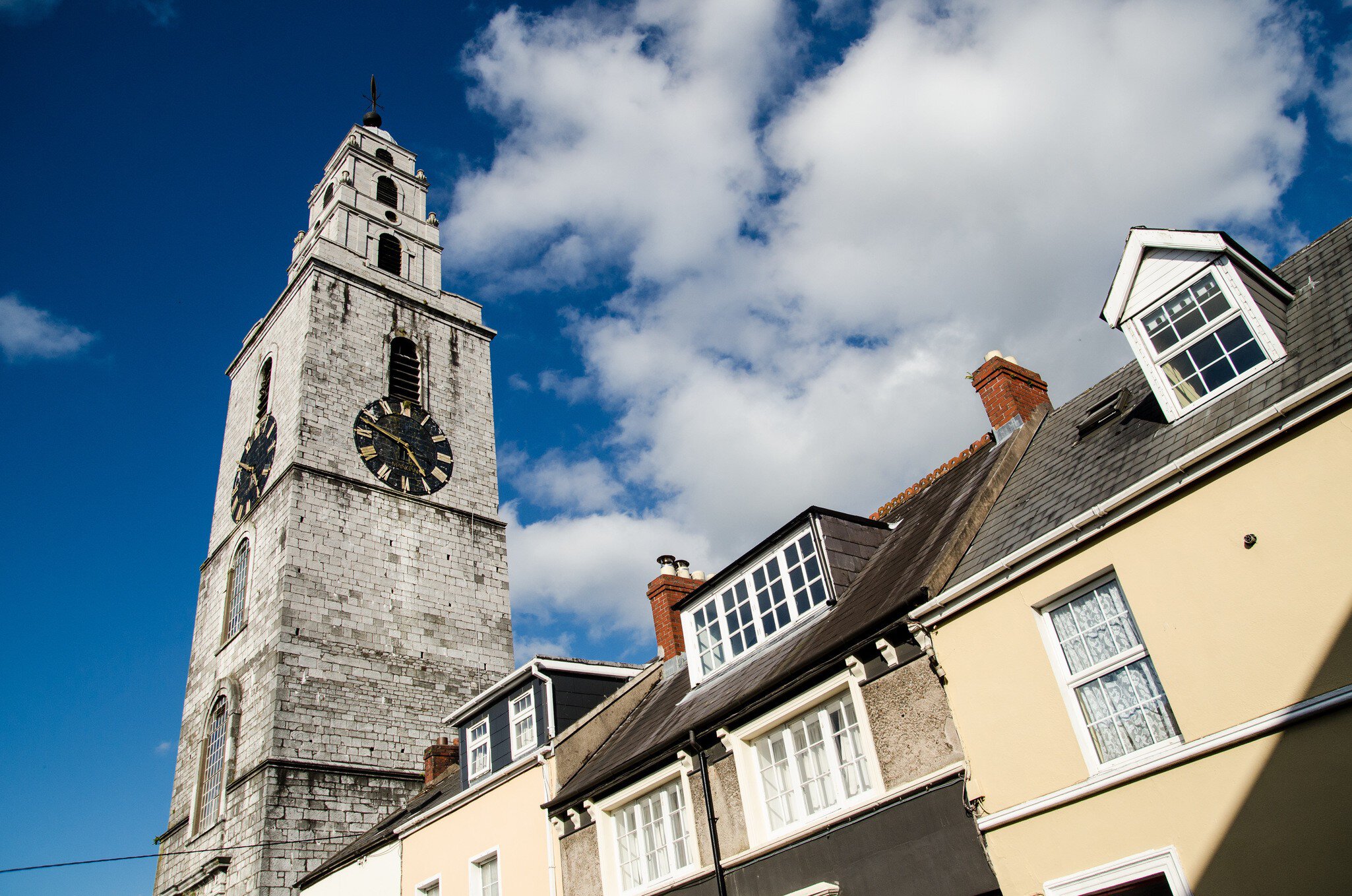 Clock tower at Church of St. Anne in County Cork, Ireland.  Low angle with blue sky in background.