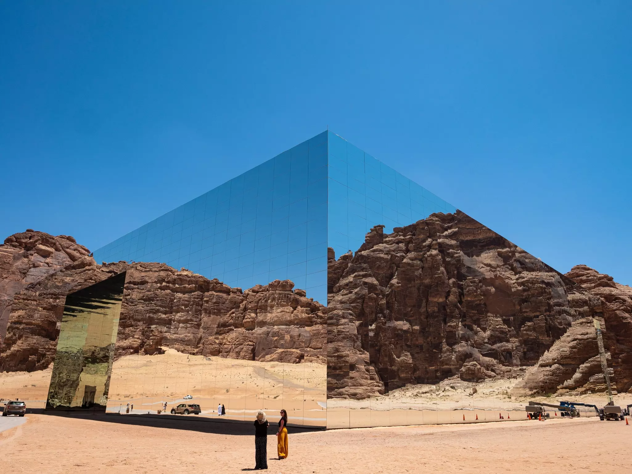 A building's mirror walls reflect and blend into the surrounding desert landscape.