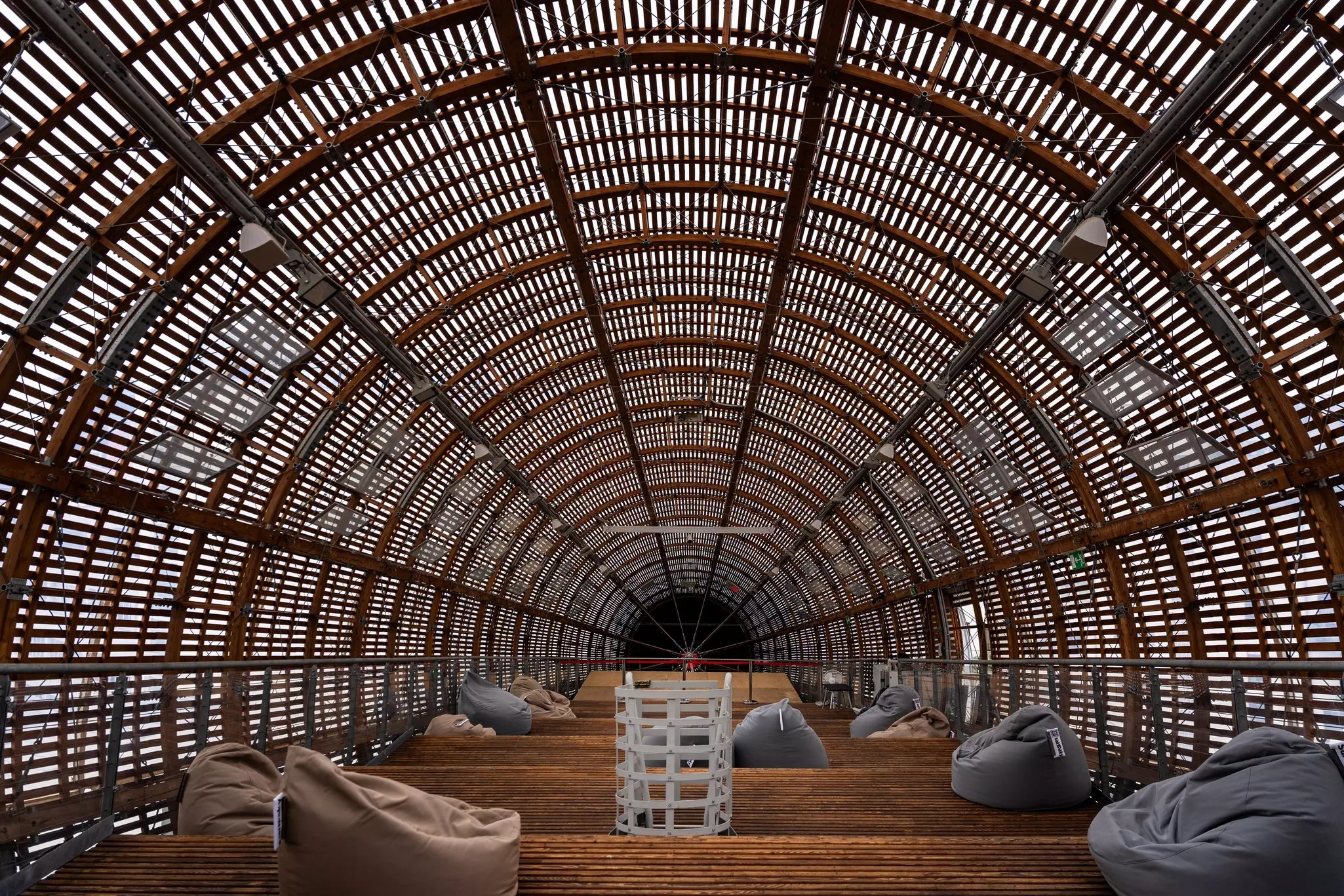 The interior of a structure made from wooden slats with light shining through.