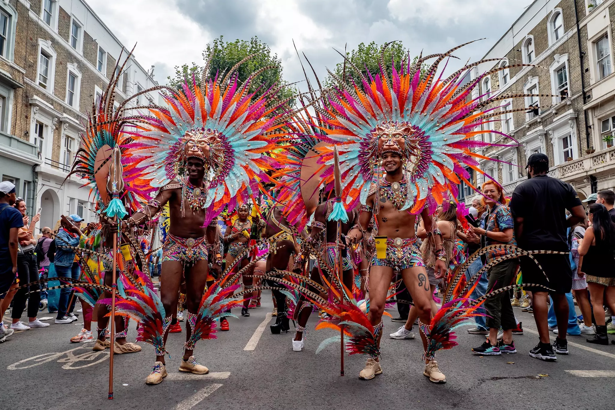 People dressed in Caribbean carnival costumes made of feathers in different colors.