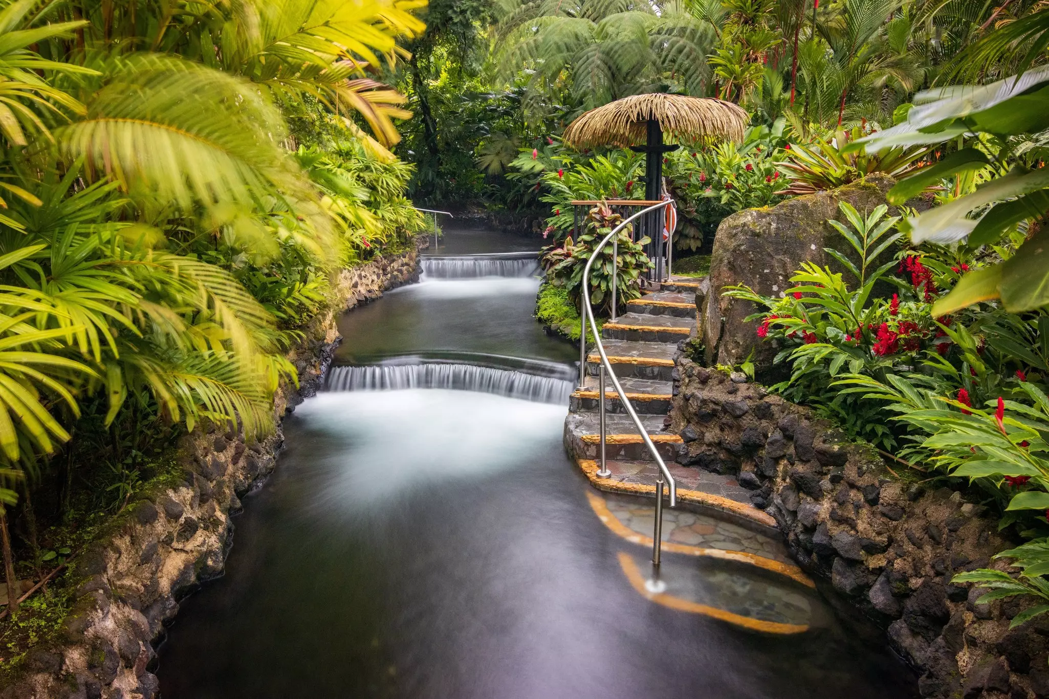 The natural hot springs of Tabacón with a stone staircase leading to the water.