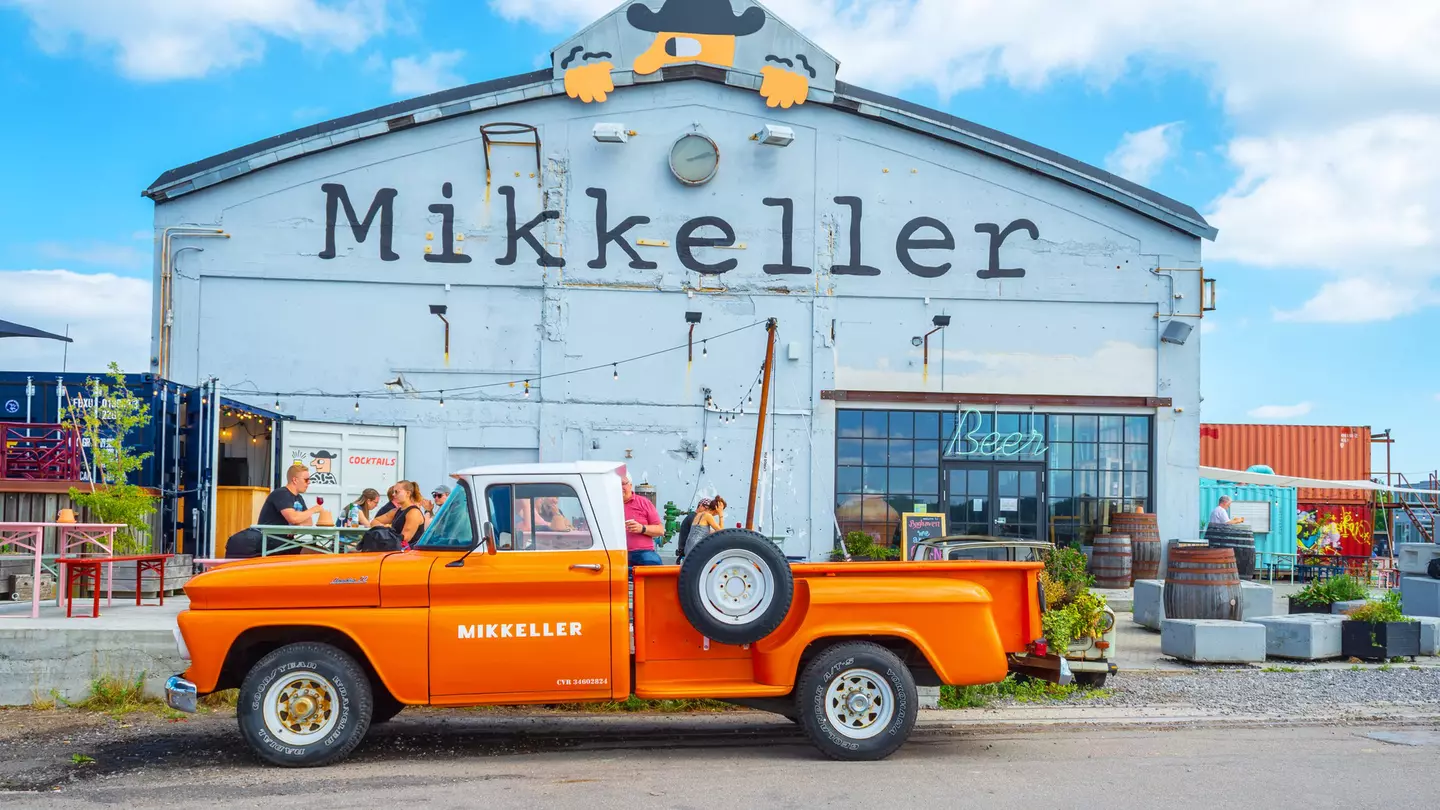 An orange retro car parked outside the Mikkeller bar at Reffen street food market.