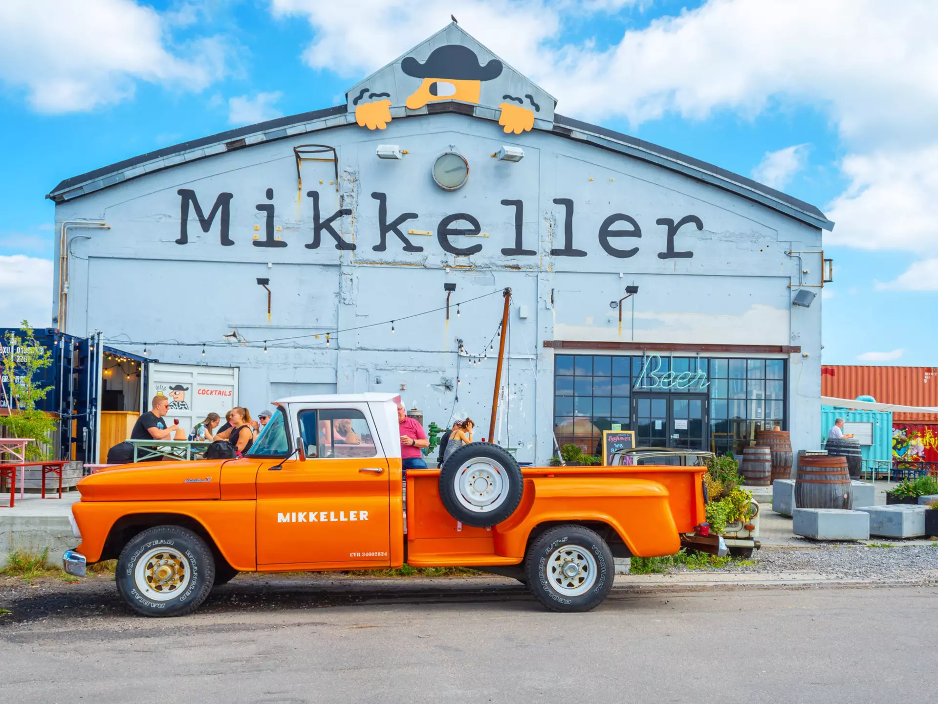 An orange retro car parked outside the Mikkeller bar at Reffen street food market.