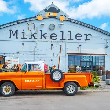 An orange retro car parked outside the Mikkeller bar at Reffen street food market.