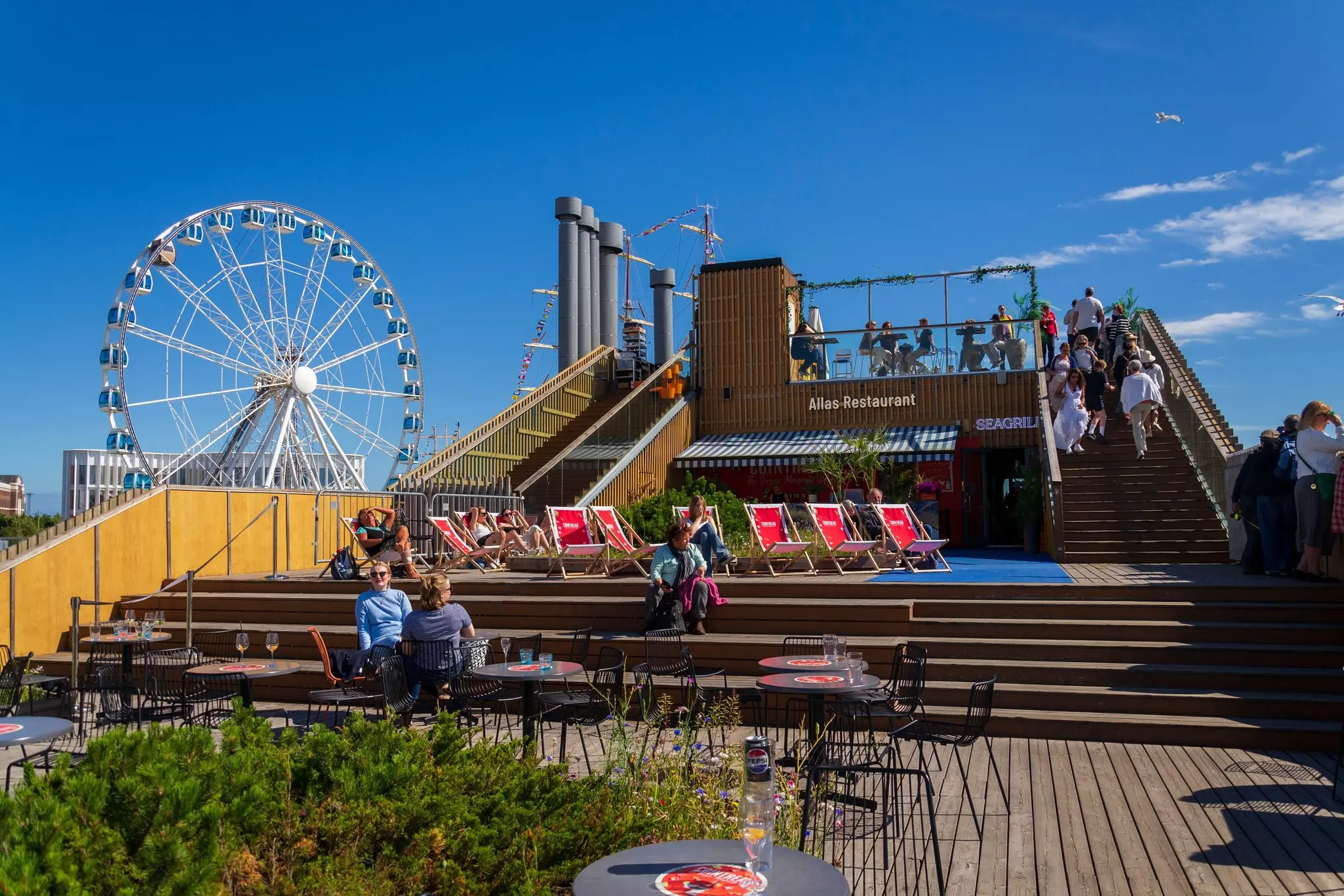 A busy restaurant deck backed by a Ferris wheel