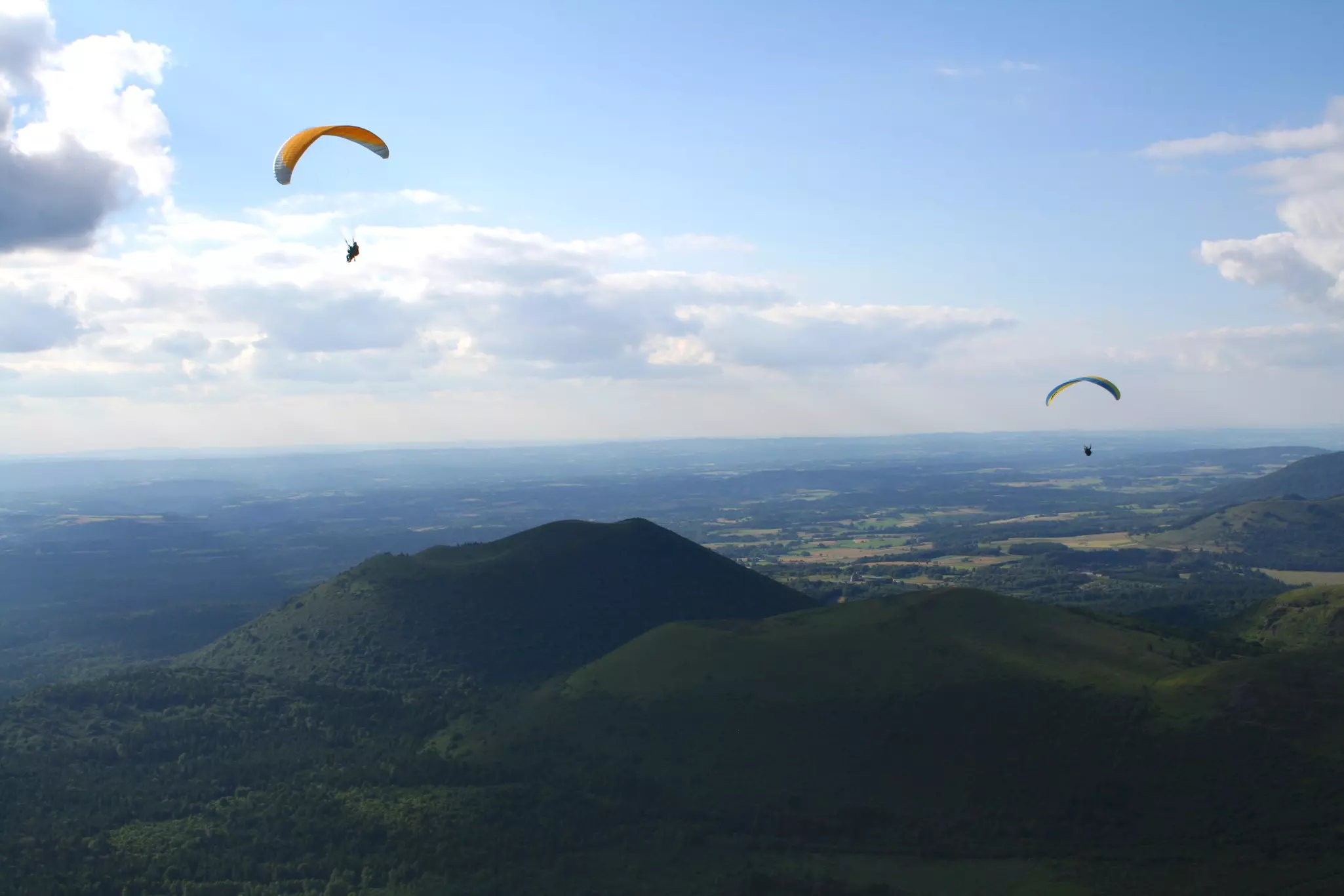Paragliders sailing above a black volcanic landscape.