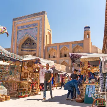 Man walking through an outdoor market lined with stalls of textiles and other products