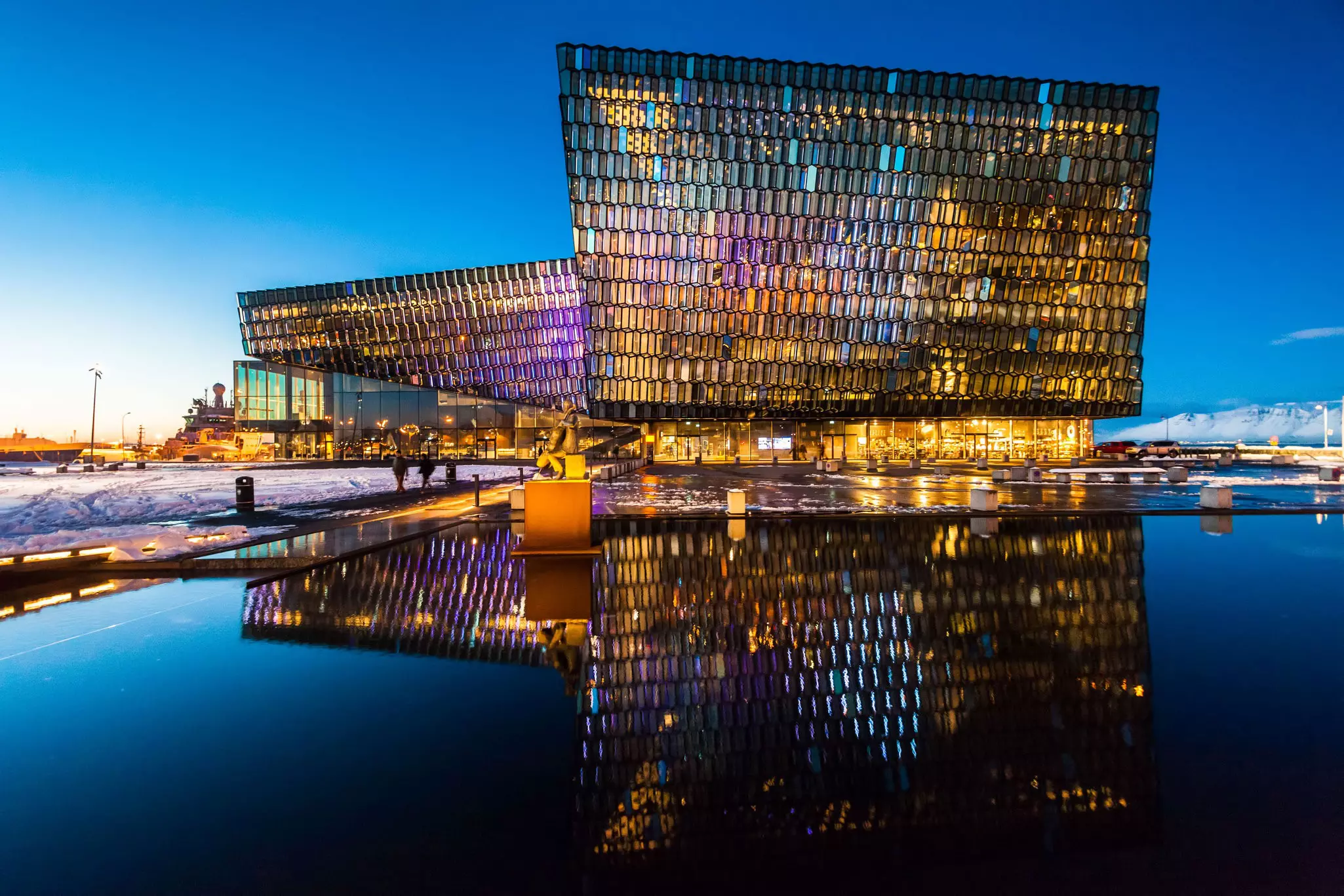 Exterior of a modern waterside concert hall illuminated during twilight